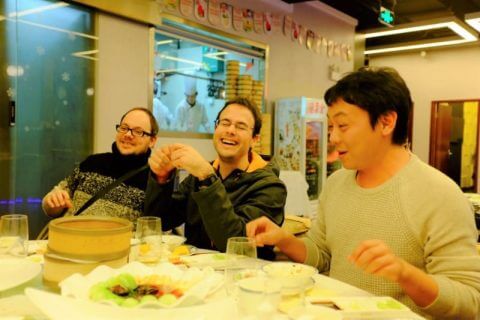 Teachers and students laughing at the table at a Beijing roast duck dinner