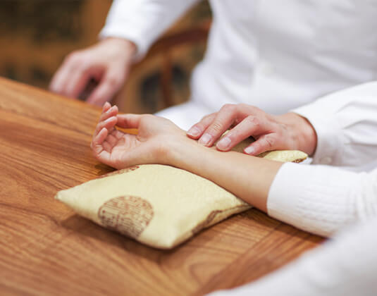 A TCM doctor examining the pulse of a patient